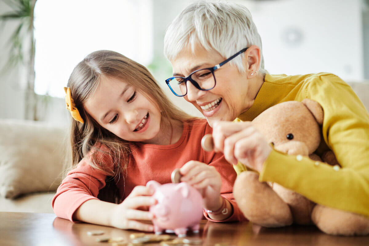 Grandmother and grandchild putting coins in a piggy bank